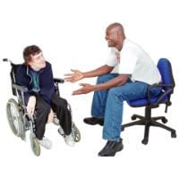 An advocate who is talking to their client who is sitting in a wheelchair.